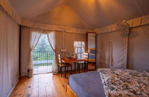 a bedroom with a bed and a desk and a window at Paradise Pool Resort in Nainital