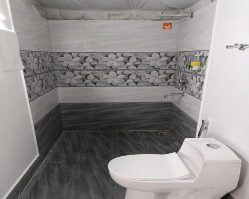 a bathroom with a toilet and a stone wall at Paradise Pool Resort in Nainital