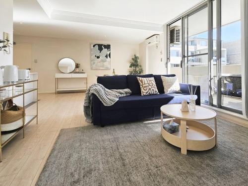 a living room with a blue couch and a table at Cozy 2-bedroom Apartment, Free Parking, close to Olympic park in Sydney