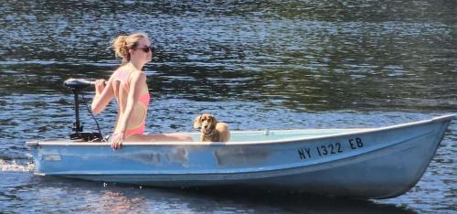 a woman and a dog sitting in a boat on the water at Stabbin Cabin #2 on Grant Island - Hot Tub, Boat, Pet Friendly in Glenfield