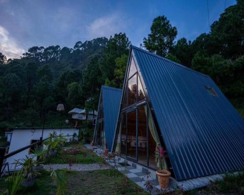a house with a blue roof and a garden at Paradise Pool Resort in Nainital