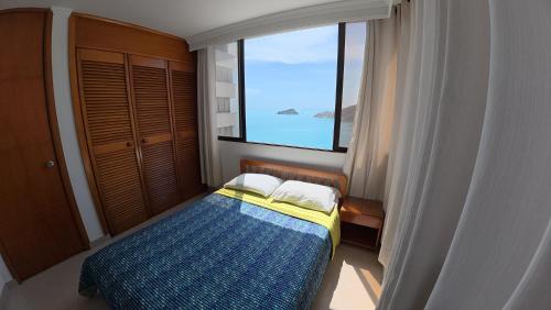 een slaapkamer met een bed en een groot raam bij Rivas Apartamentos Santa Marta in Santa Marta