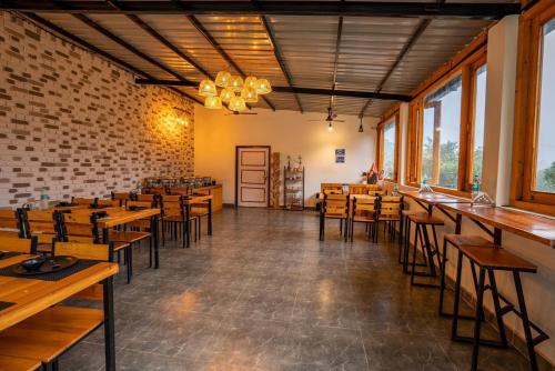 a restaurant with wooden tables and chairs and windows at Paradise Pool Resort in Nainital