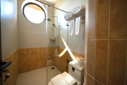 a bathroom with a toilet and a shower with a window at Naraco Homestay Hoi An in Cam Thanh