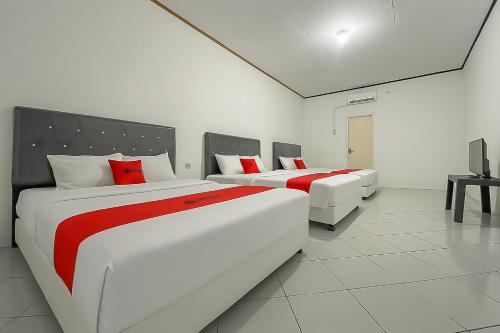 two beds in a white room with red pillows at RedDoorz at Pantai Sayangheulang Garut 2 in Cilauteureun