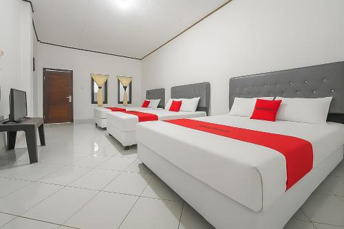 two large beds in a room with red pillows at RedDoorz at Pantai Sayangheulang Garut 2 in Cilauteureun