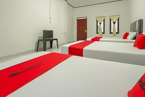 a bedroom with two beds and a television in it at RedDoorz at Pantai Sayangheulang Garut 2 in Cilauteureun