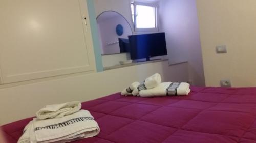 a bedroom with a purple bed with towels on it at Villa Eden Home Holiday in Santa Margherita di Pula
