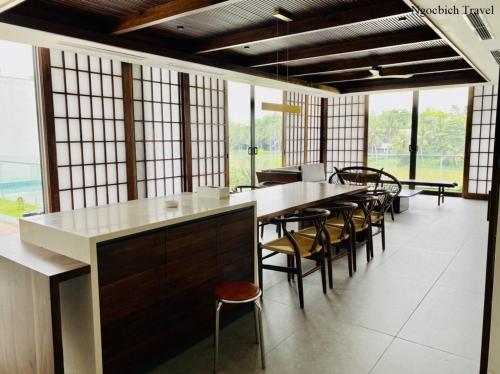 a large room with a bar with chairs and windows at Flamigo Dai Lai Resort - Villa Chủ Tự Doanh in Ngọc Quang