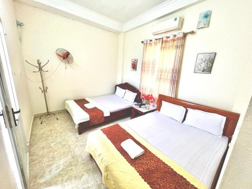 a small room with two beds and a window at Nhà Nghỉ Biển Xanh in Dao Co To