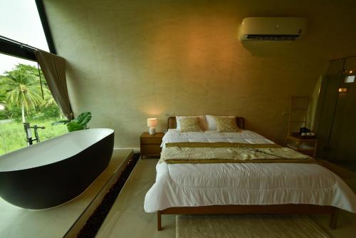 a bedroom with a bed and a bath tub and a television at Take Time Nature Resort in Ban Tha Sai