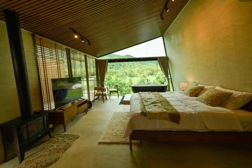 a bedroom with a large bed and a tv in it at Take Time Nature Resort in Ban Tha Sai