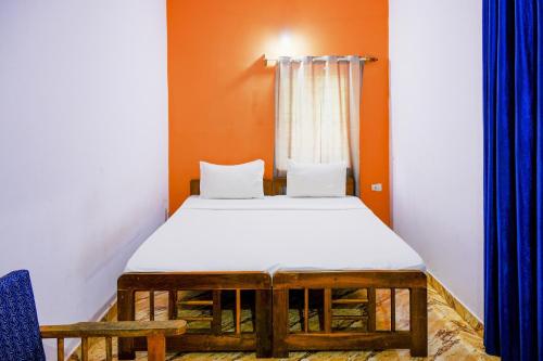 a bed in a room with orange walls and blue curtains at Hotel O Mahamaya Holiday Inn in Goa