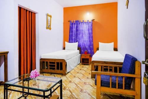 a room with two beds and a glass table at Hotel O Mahamaya Holiday Inn in Goa