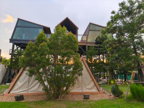 a tree house with a tent in a yard at Take Time Nature Resort in Ban Tha Sai