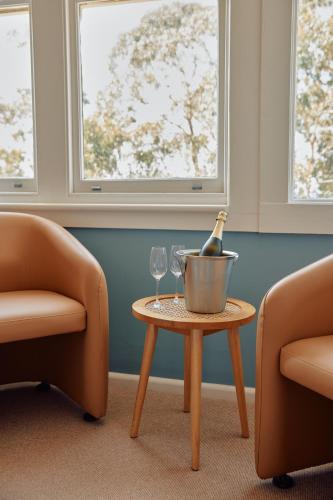 a bottle of champagne in a bucket on a table with two chairs at Lorne Hotel in Lorne