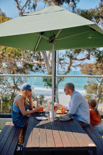 a group of people sitting at a table under an umbrella at Lorne Hotel in Lorne
