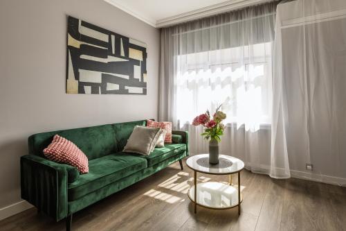a living room with a green couch and a table at Velvet Apartment in Rīga