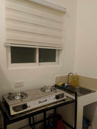 a kitchen with a stove and a sink and a window at Valor Ain Villa in Tarlac
