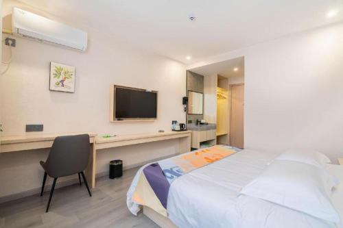 a bedroom with a bed and a desk with a television at Shell Hotel Wuxi Huishan District Chang'an Town in Wuxi