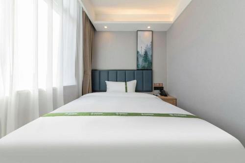 a bedroom with a white bed and a window at GreenTree Inn Express Qingdao Jiaodong International Airport in Qingdao