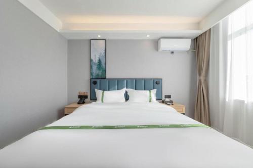 a bedroom with a large white bed and a window at GreenTree Inn Express Qingdao Jiaodong International Airport in Qingdao