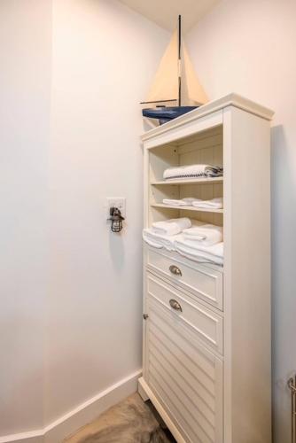 a closet with a white cabinet with white towels at Sunset Breeze Marsh View Treehouse Retreat in Fripp Island