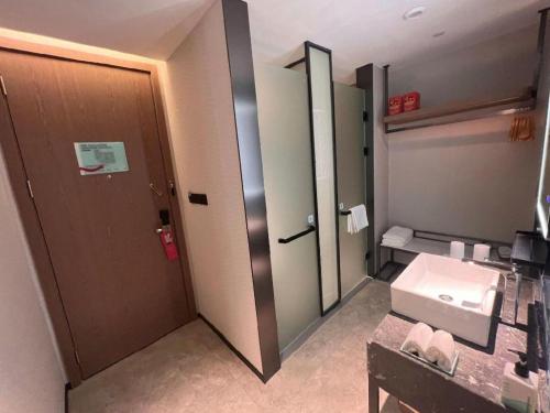 a bathroom with a door and a sink and a mirror at Echarm Hotel Changsha Huanghua Airport in Changsha