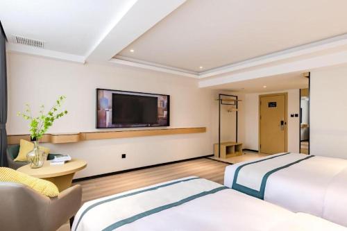 two beds in a hotel room with a flat screen tv at City Comfort Inn Kunming Dashuying Yejin Hospital Wangdaqiao in Kunming