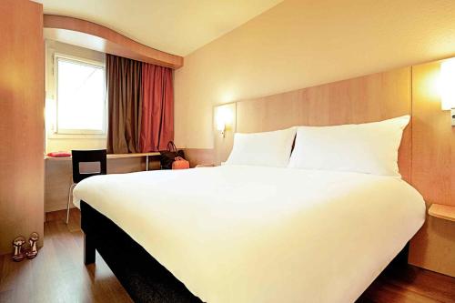 a large white bed in a hotel room at ibis Issoire in Issoire