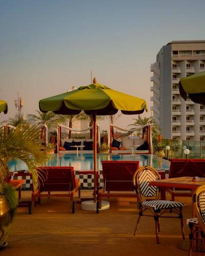 a pool with tables and chairs and an umbrella at Tribe Pattaya in Jomtien Beach