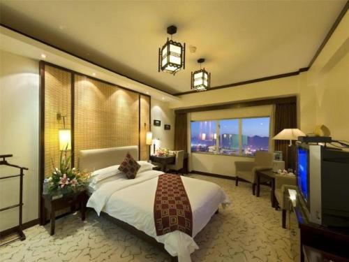 a hotel room with a bed and a television at New Era Hotel in Kunming