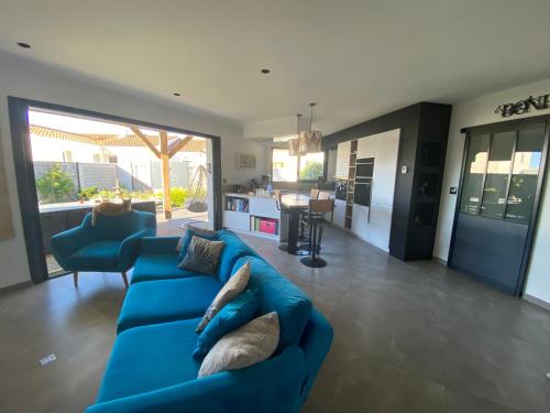 un salon avec un canapé bleu et une cuisine dans l'établissement Villa GANESH à ROYAN, à Royan
