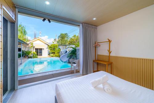 a bedroom with a bed and a large window with a swimming pool at Cozy Gray Garden in Pattaya