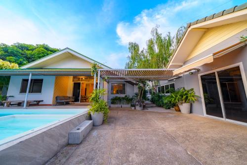 a house with a swimming pool in front of it at Cozy Gray Garden in Pattaya