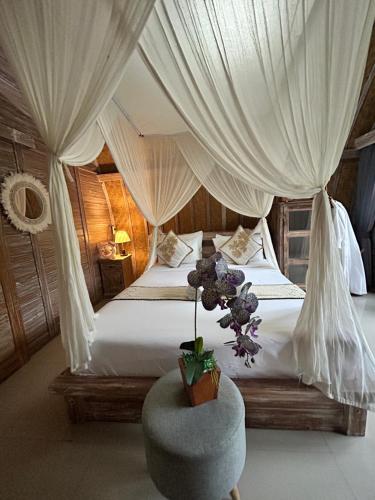 a bedroom with a bed with curtains and a chair at Batur cottage in Kubupenlokan