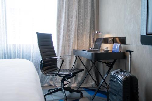 a desk with a laptop and a chair in a room at Novotel Singapore On Stevens in Singapore
