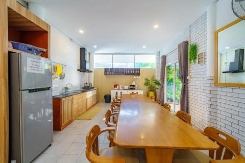 a kitchen with a long wooden table and a refrigerator at Cozy Gray Garden in Pattaya