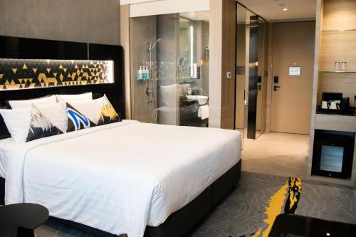 a bedroom with a large white bed and a bathroom at Novotel Singapore On Stevens in Singapore