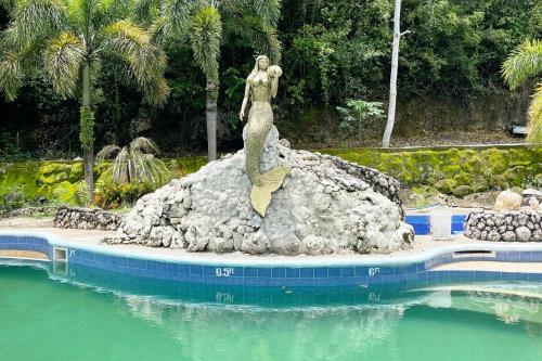 a mermaid statue sitting on a rock in the water at La Puerta Al Paraizo Guimaras powered by Cocotel in Guimaras