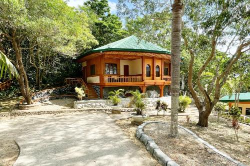 a house with a green roof in a yard at La Puerta Al Paraizo Guimaras powered by Cocotel in Guimaras