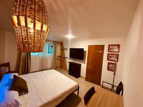 a bedroom with a bed and a table and a chandelier at Loft perfecto para foro sol aeropuerto GNP in Mexico City