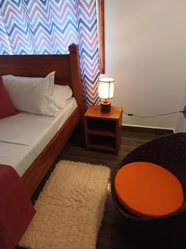 a bedroom with a bed and a table with a lamp at La Banane Rouge Self Catering in La Digue