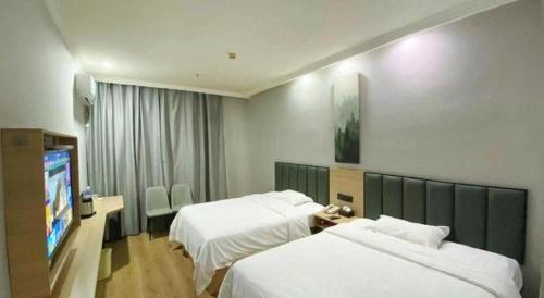 a hotel room with two beds and a flat screen tv at GreenTree Inn Taizhou New District Hospital of Renmin Hospital Mingliu Express Hotel in Jiuligou
