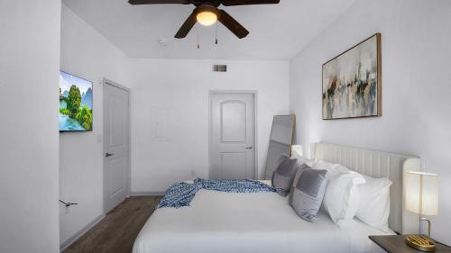 a white bedroom with a bed and a ceiling fan at Charming 1BD Haven I Frisco I Pool, Gym, Work Space in Frisco