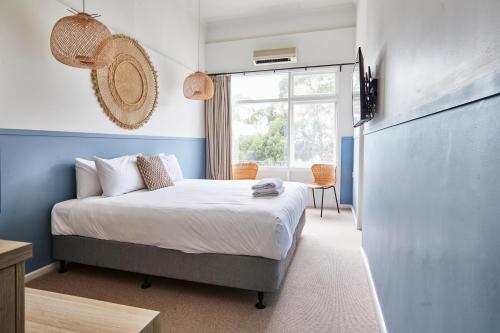 a bedroom with a bed with blue walls and a window at Lorne Hotel in Lorne