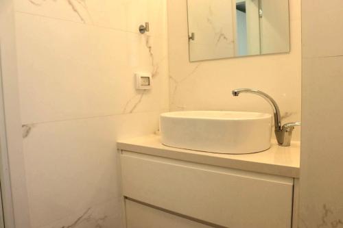 a white bathroom with a sink and a mirror at הנופש הצפוני in Qiryat Shemona