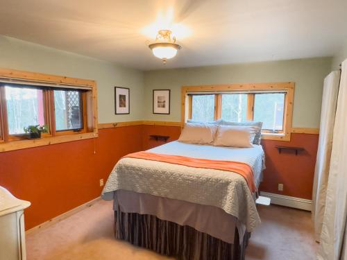 a bedroom with a bed and two windows at Moose Mountain Cabin- Cozy retreat with aurora views in Fairbanks