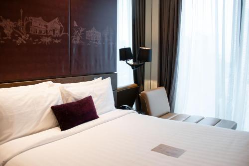 a hotel room with a bed and a chair at Mercure Singapore On Stevens in Singapore