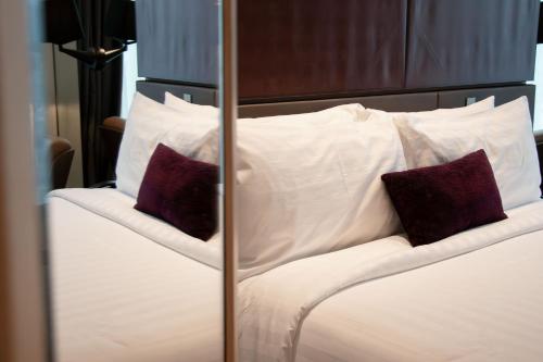a bed with white sheets and purple pillows at Mercure Singapore On Stevens in Singapore